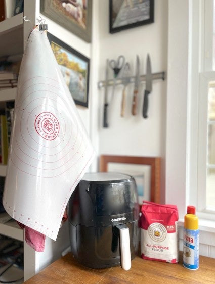 Rolling mat hanging from a hook on the wall next to a wooden work table.